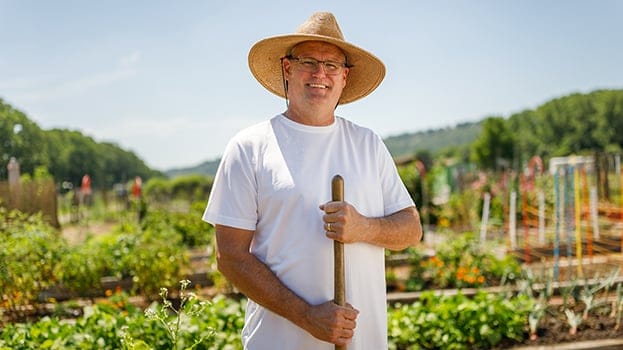 Man in a garden holding a gardening tool