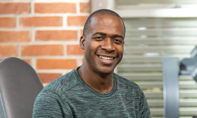 Man smiling while sitting in a fitness or health setting.